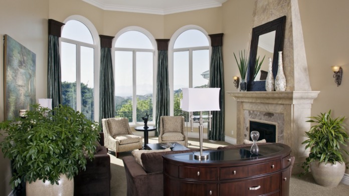 Interior lounge area with arched windows, stone fireplace, comfortable seating, plants, and refined furnishings for residents