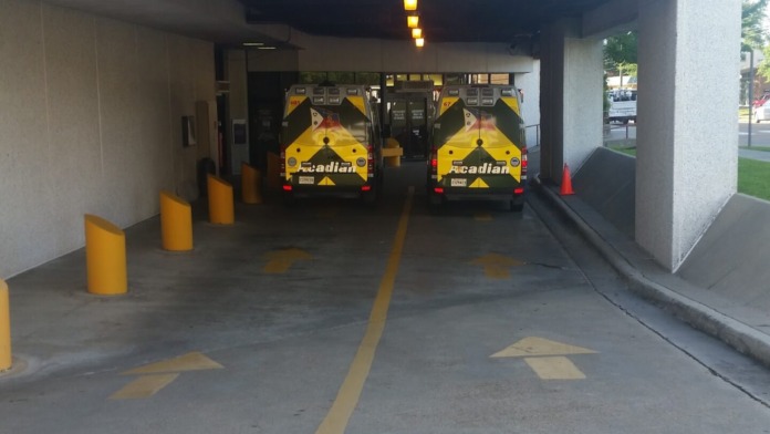 Exterior emergency entrance with ambulances in covered bay, emergency signage, and protective bollards
