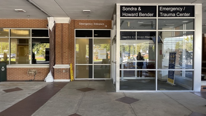 Interior hallway showing emergency entrance signage, directional wayfinding, and glass doors to emergency treatment areas