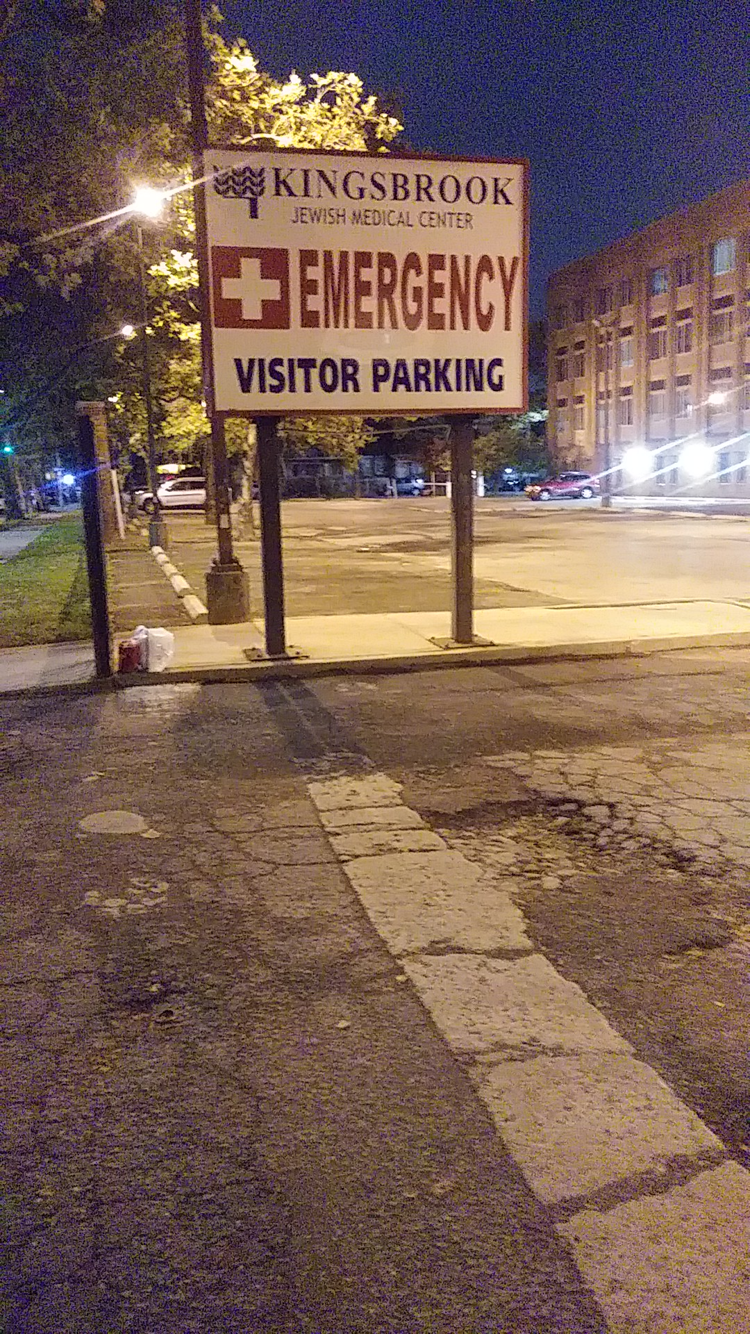 Evening exterior view of emergency visitor parking sign with facility building in background