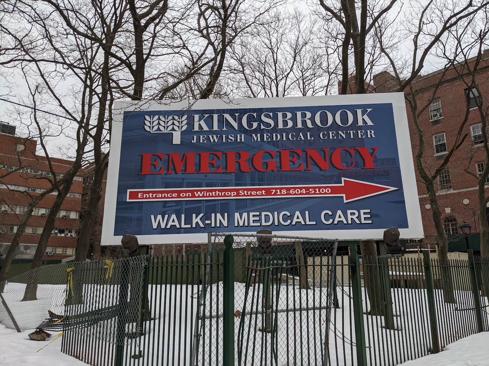 Outdoor signage showing emergency entrance directions with red arrow and facility information