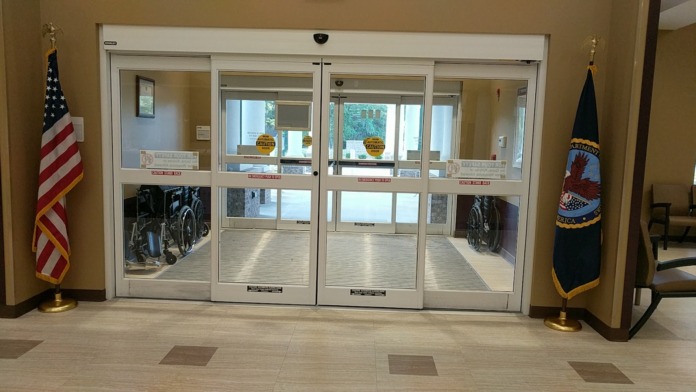 Interior automatic glass doors with emergency push buttons, American flags, and military insignia on sides