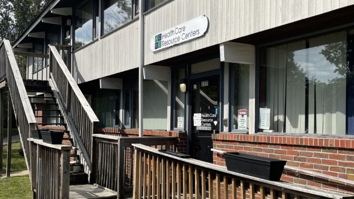 Side entrance showing wooden ramp, metal railings, and entrance signage for healthcare resource center