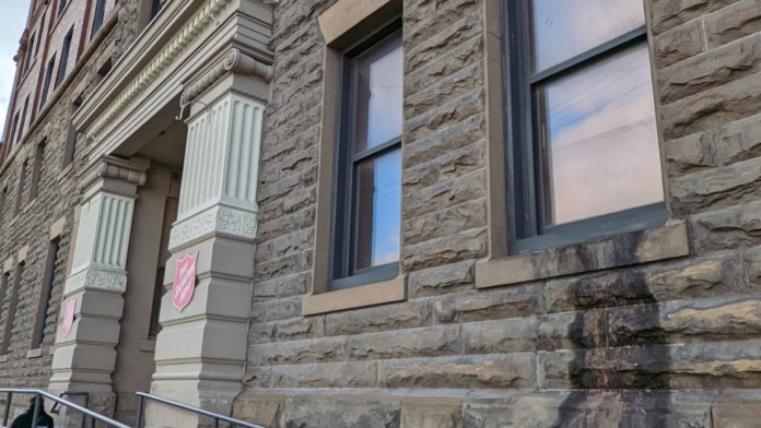 Exterior stone entrance facade showing building name sign and large windows with railing