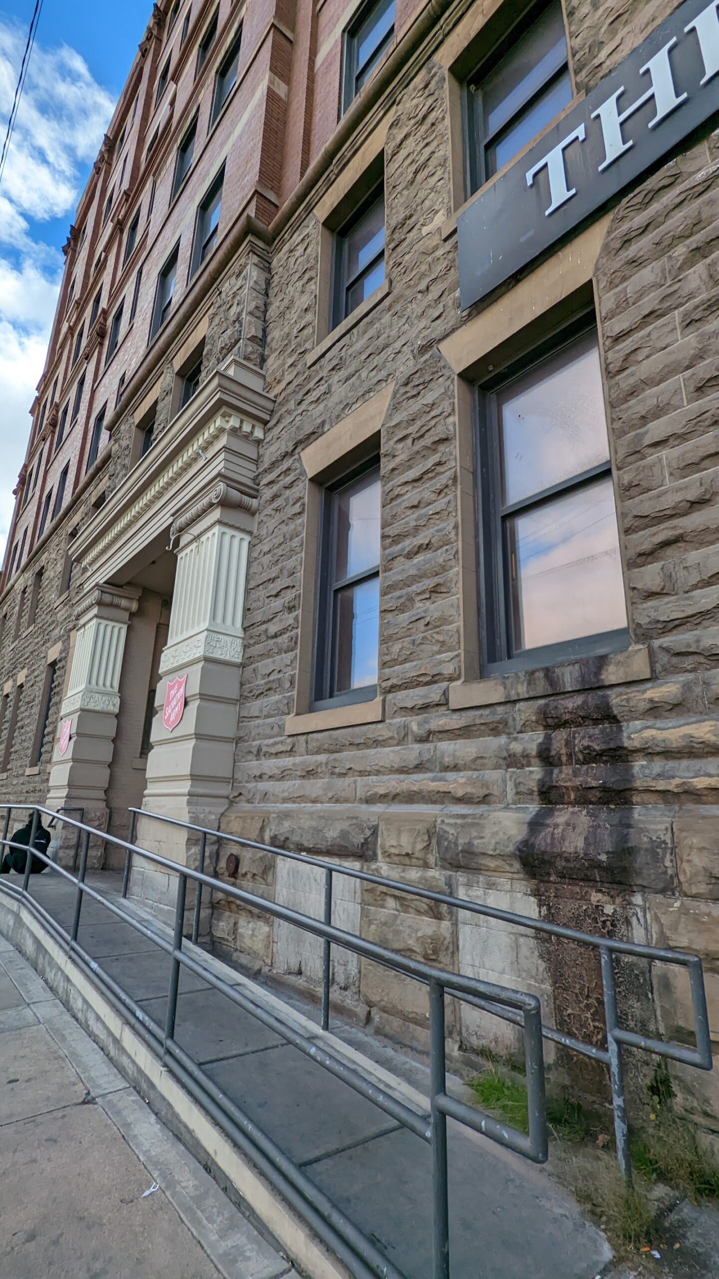 Exterior stone entrance facade showing building name sign and large windows with railing