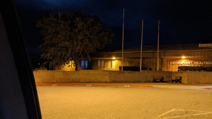 Exterior nighttime view of facility with parking area, illuminated building signage, and moonlit sky