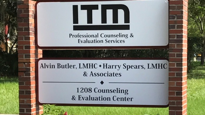Exterior signage mounted on brick pillars displaying facility address number 1208 and business information with landscaping