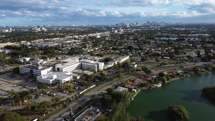 Aerial exterior view showing complete medical facility campus with building structures, parking areas, landscaping, and surrounding neighborhood