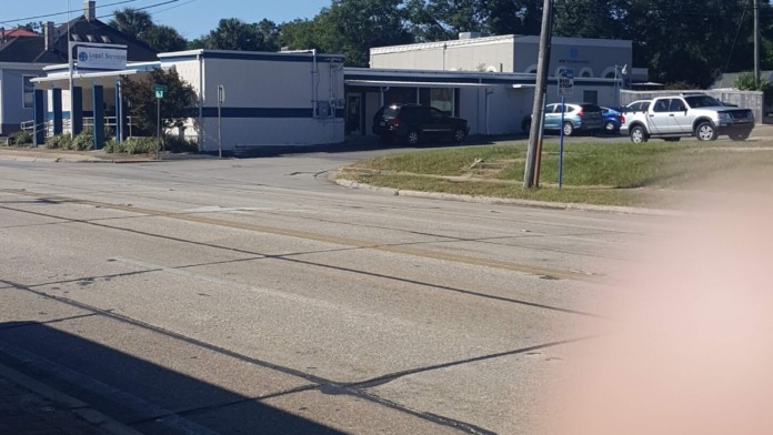Exterior view of modern white and brick treatment facility building with large windows, parking lot with vehicles, and surrounding vegetation