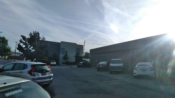 Exterior view of multi-unit facility buildings with parking area showing multiple parked vehicles and overhead lighting