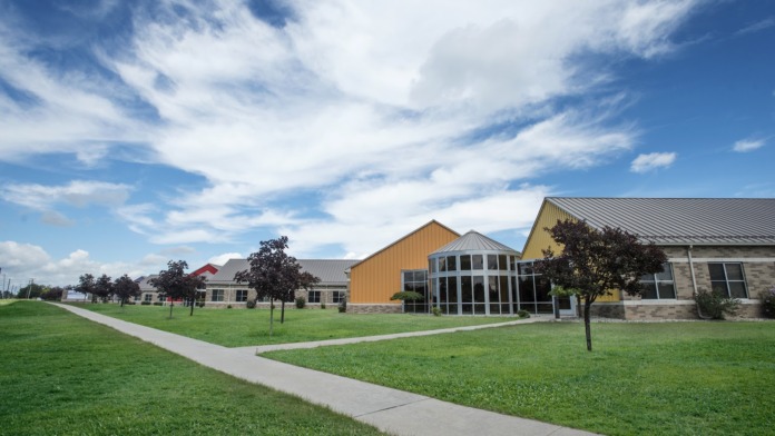 Exterior view of treatment facility campus with multiple buildings, manicured lawns, landscaping, and walking paths