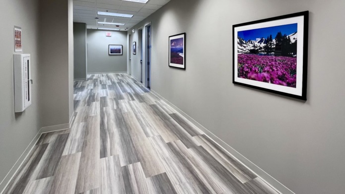Interior hallway with framed landscape photographs on walls, wood grain flooring, and consistent lighting throughout