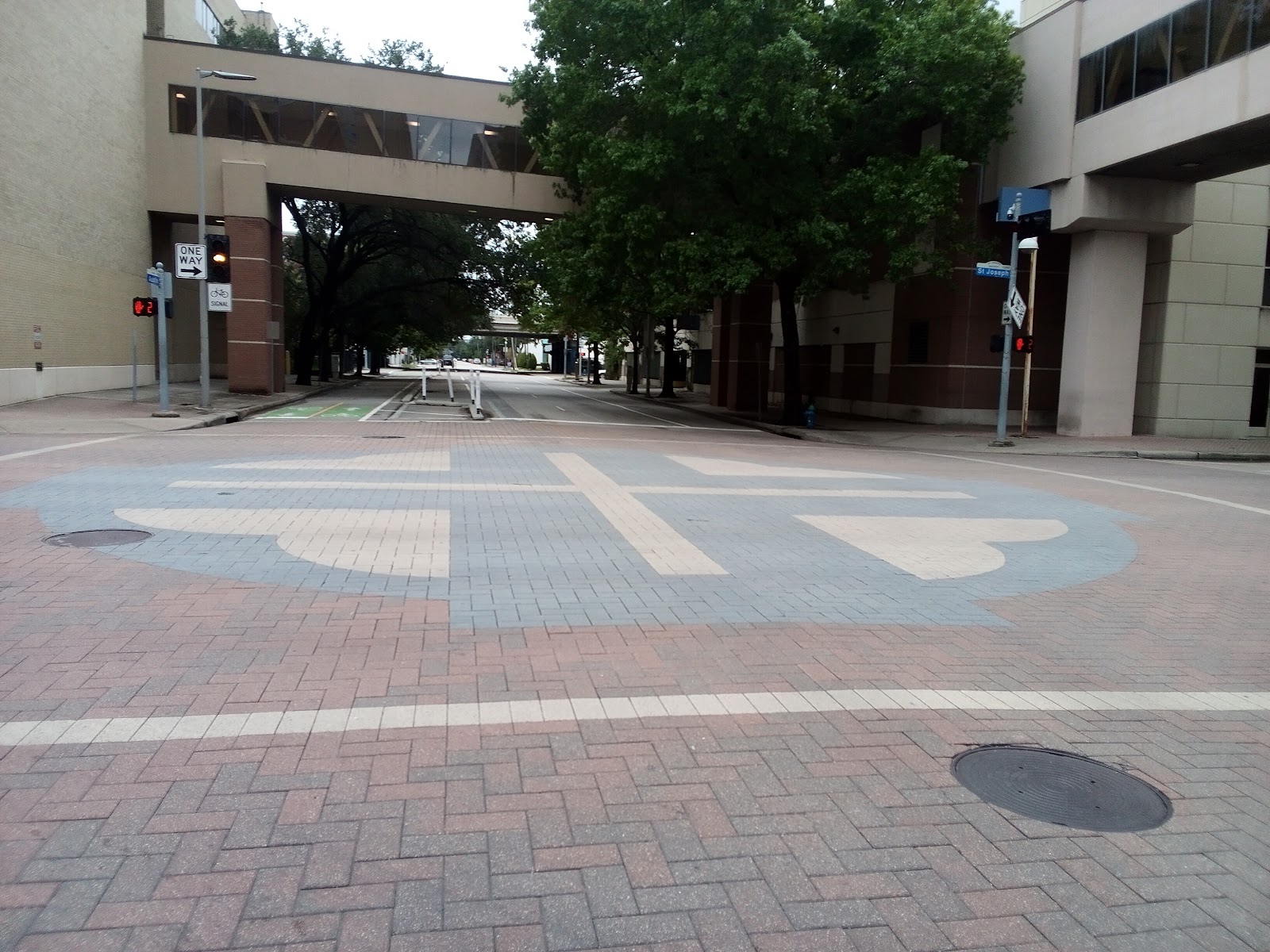 Exterior courtyard pathway with patterned paving, shaded trees, and adjacent building structures
