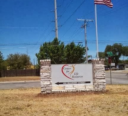 Exterior facility sign for Center for Life Resources with American flag, landscaped grounds, and clear blue sky