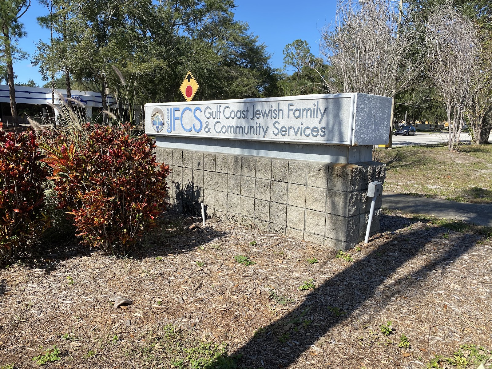 Exterior facility sign reading Gulf Coast Jewish Family and Community Services with landscaping and trees