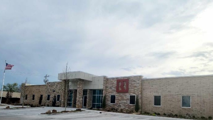 Exterior view of treatment center entrance at dusk with stone facade, red roof, windows, and landscaping visible