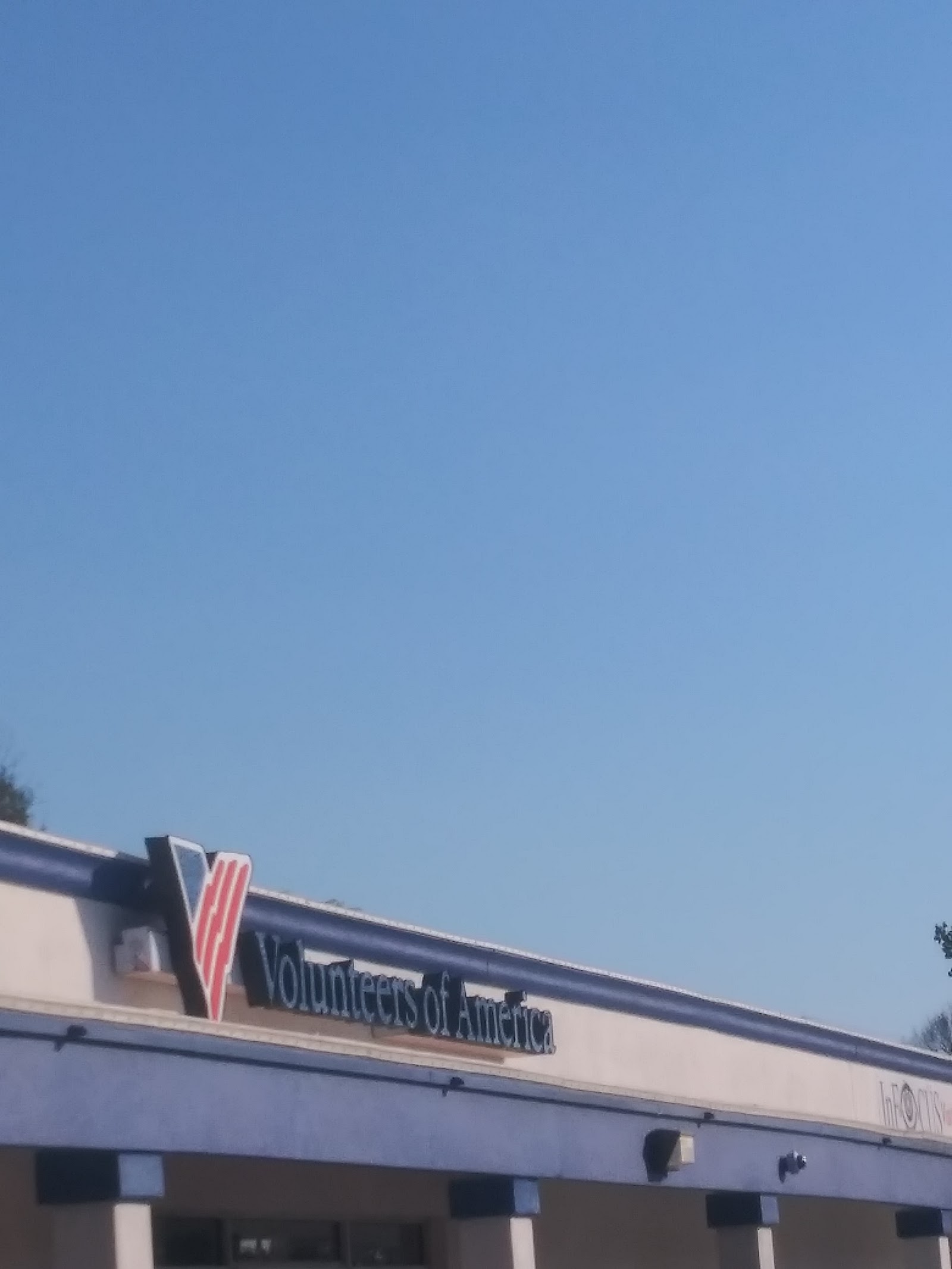 Exterior building view showing partial Volunteers of America signage against blue sky
