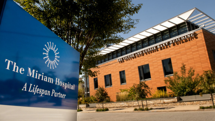 Exterior view showing The Miriam Hospital signage, brick building facade, and landscaping