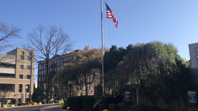 Outdoor view of medical center with American flag, landscaped grounds, and building exterior with clear sky