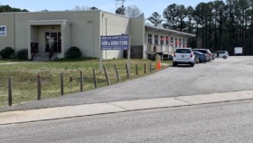 Exterior view of treatment facility buildings with parking area, landscaping, and adjacent thrift store signage