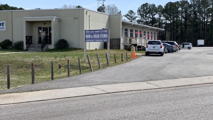 Exterior view of treatment facility buildings with parking area, landscaping, and adjacent thrift store signage