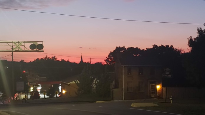 Exterior view of treatment facility building at sunset with street signage, surrounding trees silhouetted, and illuminated building windows