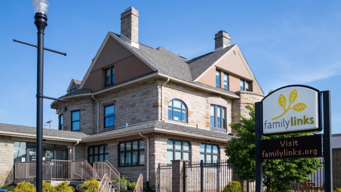 Exterior view of three-story Victorian-style stone building with multiple windows, manicured shrubs, and street lamp