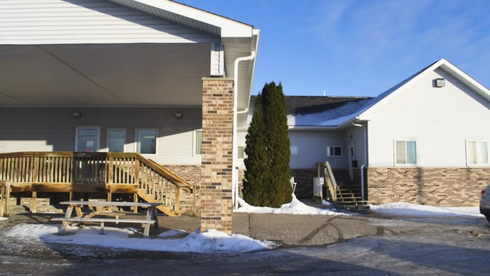 Exterior view of brick and siding treatment facility with wooden deck, picnic tables, and landscaping