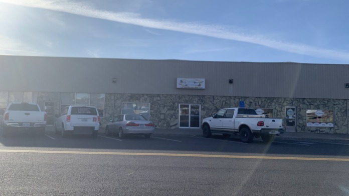 Exterior view of treatment facility showing front entrance, stone facade, windows, and parking area with vehicles