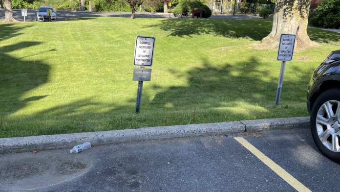 Exterior view of facility grounds with manicured lawn, mature trees, and directional signage