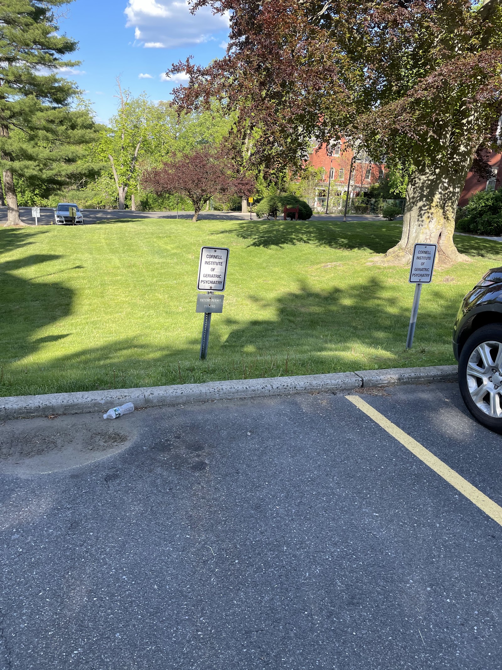 Exterior view of facility grounds with manicured lawn, mature trees, and directional signage