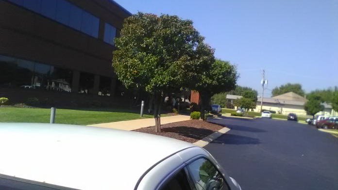 Exterior grounds showing manicured lawn, mature trees, and paved driveway with facility building in background