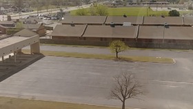 Exterior view of facility building with parking area, landscaped grounds, and surrounding area from elevated perspective