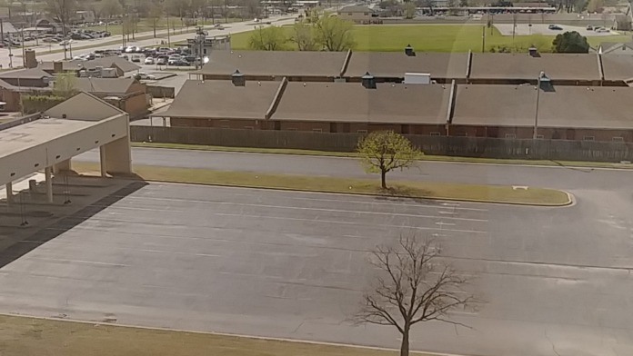 Exterior view of facility building with parking area, landscaped grounds, and surrounding area from elevated perspective