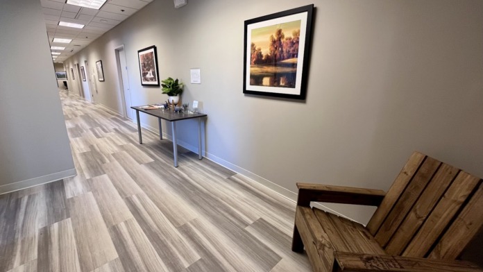 Interior corridor hallway with framed landscape artwork on walls, hardwood flooring, and natural lighting