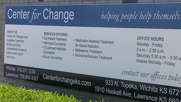 Exterior wall-mounted informational signage displaying Center for Change details, services offered, office hours, and contact information