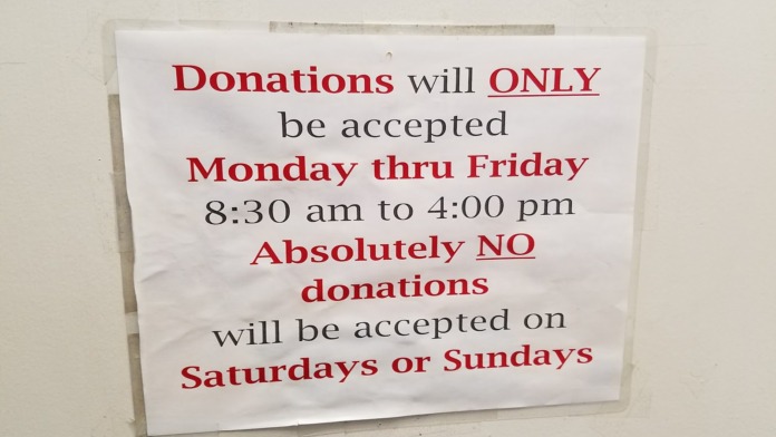 Interior wall sign displaying donation acceptance hours and operational information for facility