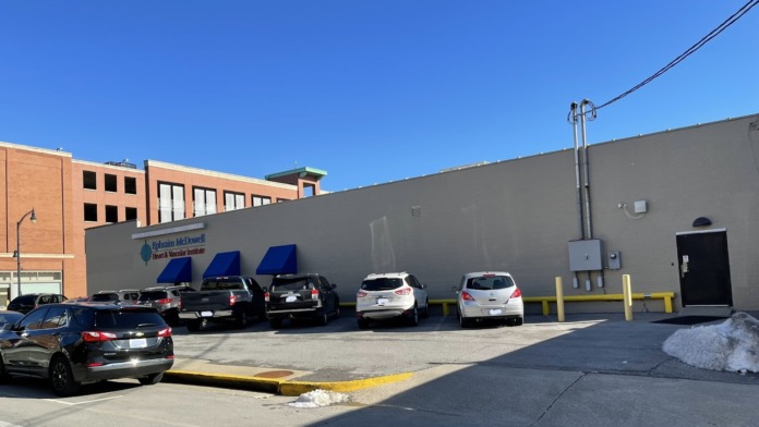 Exterior parking area with vehicles against gray institutional building wall