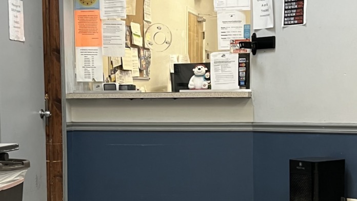 Interior reception counter with accreditation signage, informational documents, and office supplies displayed on wall