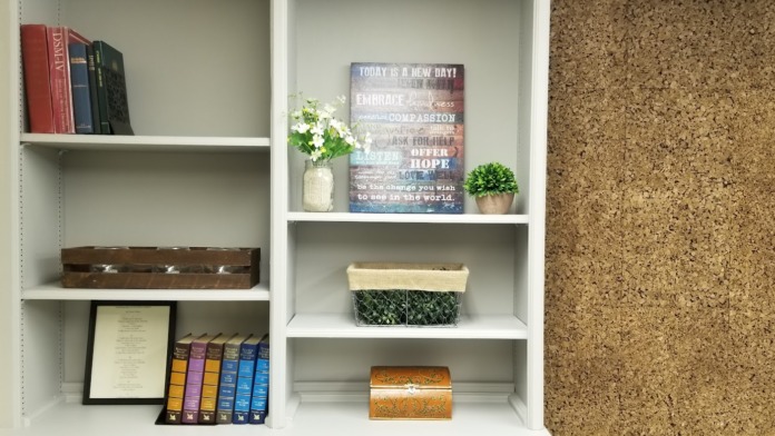 Interior shelving unit with books, motivational signage, and decorative items in facility