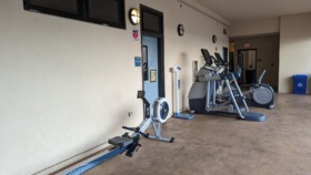 Interior fitness room with stationary bikes, elliptical machines, and exercise equipment along white walls