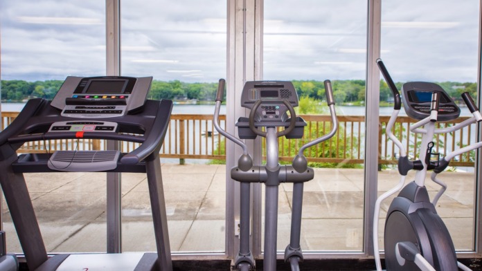 Interior fitness center featuring treadmill, elliptical machine, stationary bike and panoramic lake windows