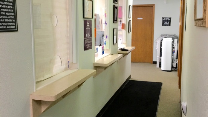 Interior hallway with reception window counter, decorative wall displays, and multiple doorways with professional signage