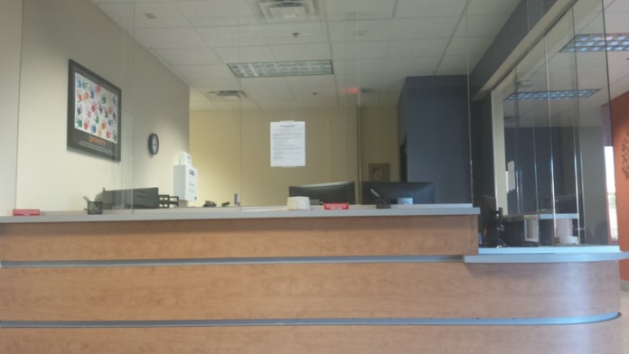 Interior reception area with curved counter desk, glass partition, and workspace