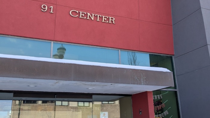 Exterior front entrance showing red panel signage reading 91 CENTER with glass doors and street-level storefront