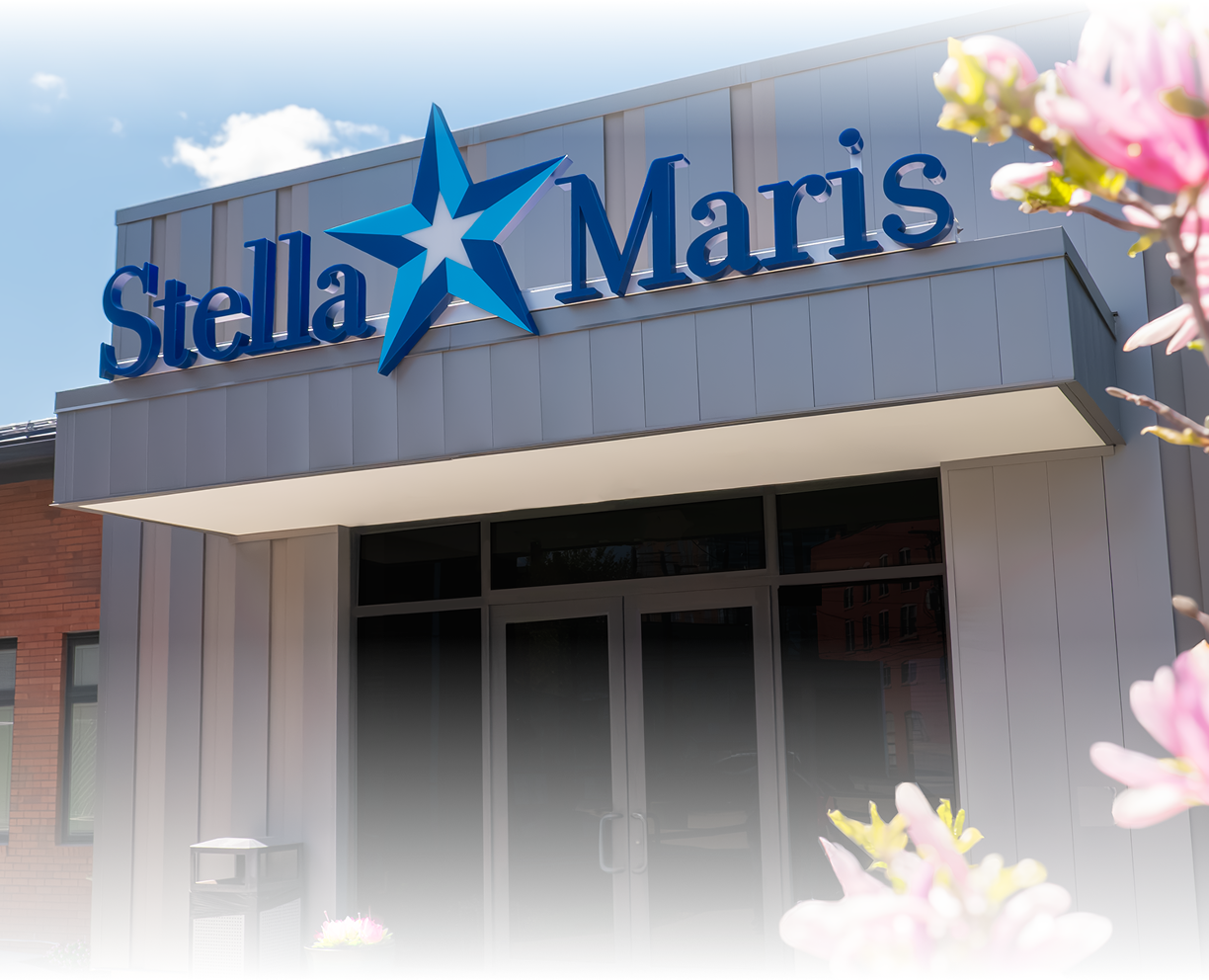 Exterior closeup of Stella Maris facility blue star logo and entrance signage with flowers