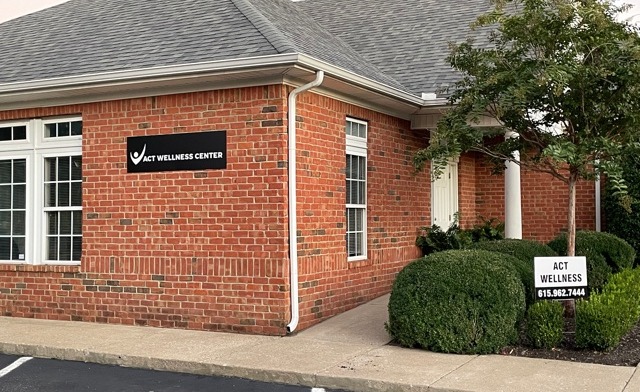 Exterior view of ACT Wellness Center brick building with main entrance, signage, and landscaped grounds