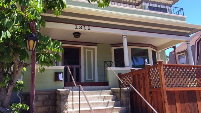 Close-up exterior view of main entrance showing address 1315, front steps, handrail, green door, and landscaping