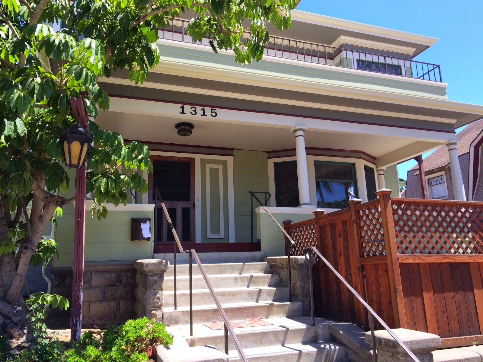 Close-up exterior view of main entrance showing address 1315, front steps, handrail, green door, and landscaping
