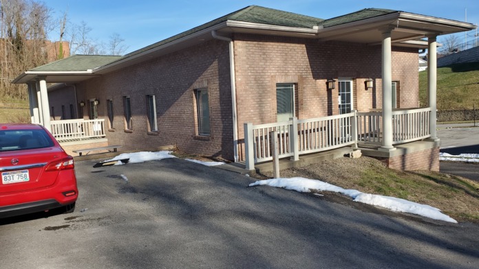 Exterior view of treatment facility entrance showing brick facade, covered porch area with white railings, and parking